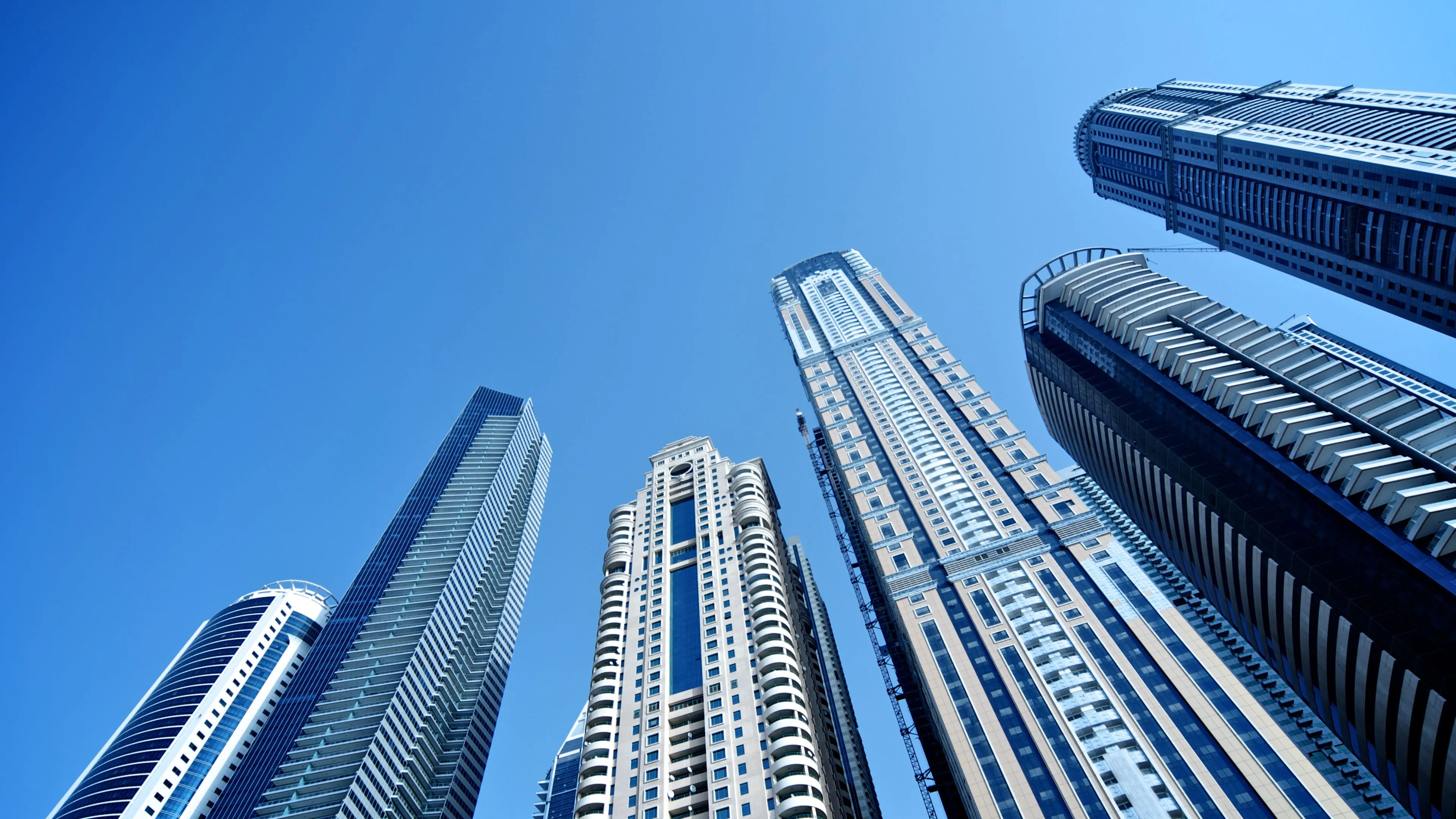 Modern glass skyscrapers rising against a blue sky, representing global markets